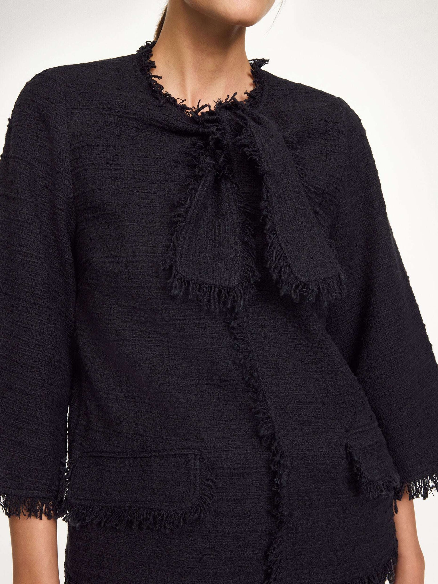 Diana Boucle Blouse in Black displayed on a hanger, highlighting its elegant silhouette and detailed design.