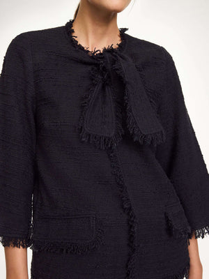 Diana Boucle Blouse in Black displayed on a hanger, highlighting its elegant silhouette and detailed design.