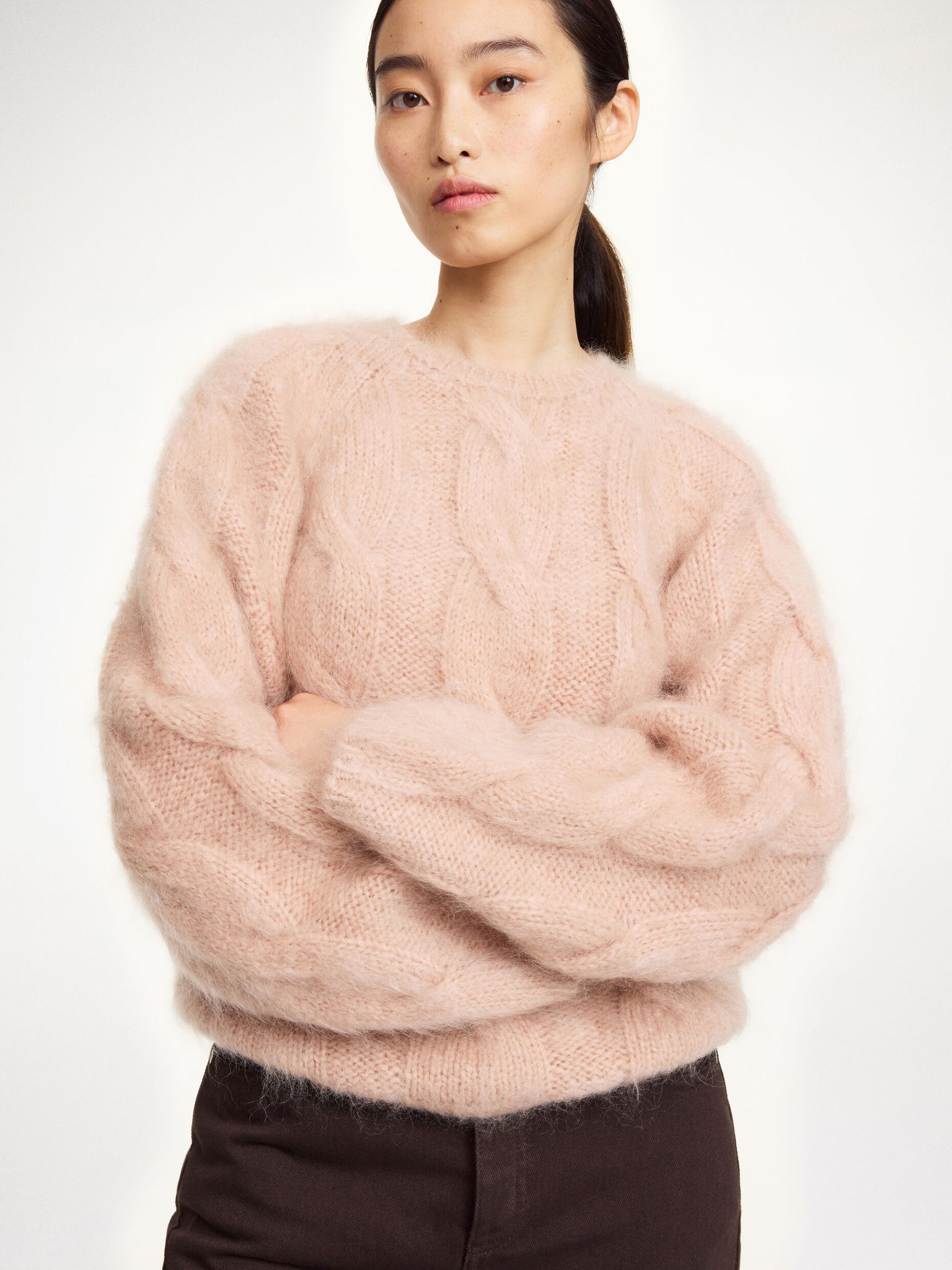 Model wearing the Elliot Sweater in Rose Dust from By Malene Birger, featuring elongated sleeves and a comfortable fit.