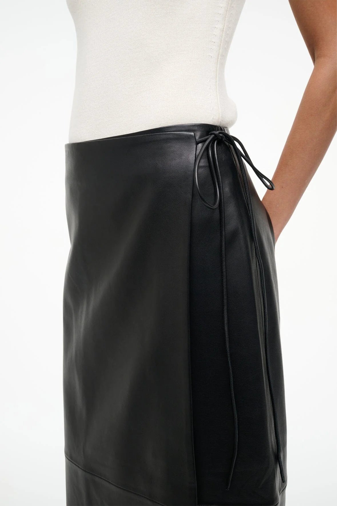 Roman Leather Wrap Skirt in Black by Staud displayed on a stylish hanger, emphasizing its elegant wrap design.