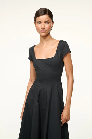Short Sleeve Wells Dress in Black styled with accessories on a minimalist background.
