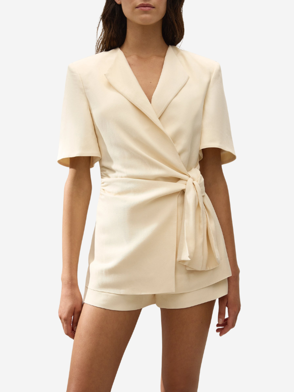 Ida Knot Blazer in Latte on a hanger, emphasizing its stylish design and beautiful creamy neutral color.