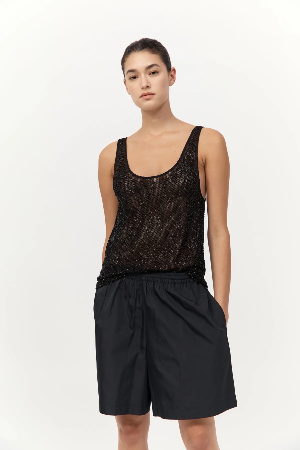 Flat lay of St. Agni Glass Beaded Mesh Top in Jet Black on a textured surface, displaying its luxurious fabric.