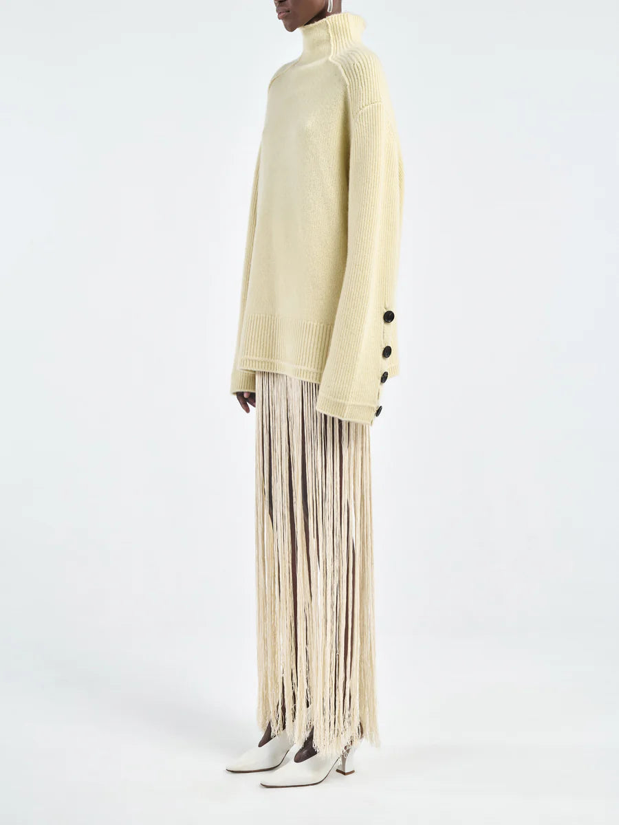 Close-up of the Primrose Yellow Button Mock Neck Sweater showcasing 3 signature corozo nut buttons at the cuff.