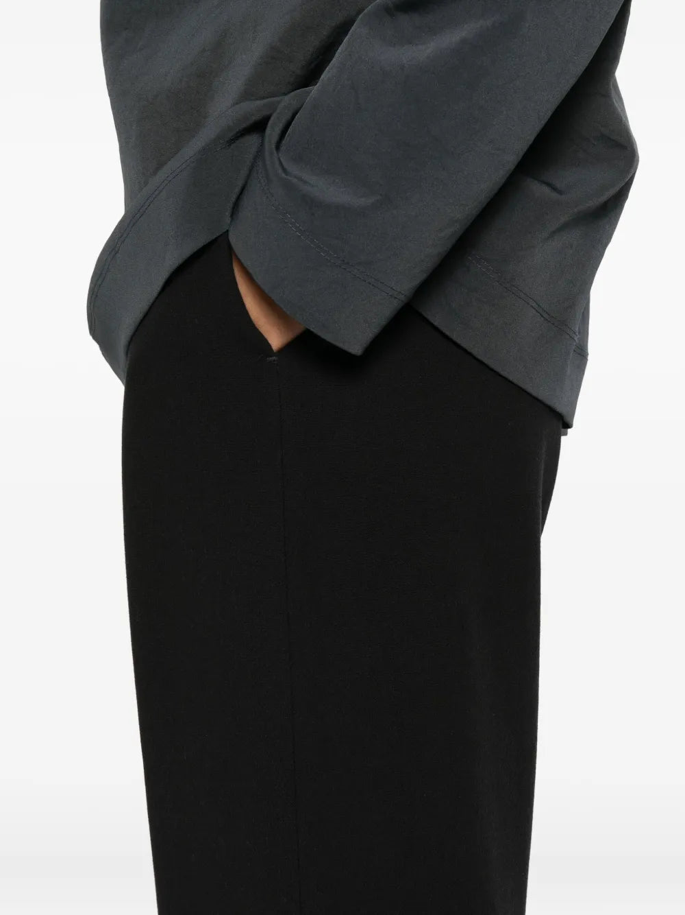 Nanushka Arvenn Pants in Black hanging neatly on a hanger, demonstrating their fluid silhouette and elegant appeal.