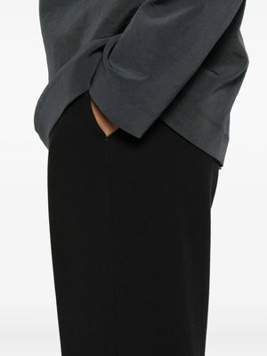 Nanushka Arvenn Pants in Black hanging neatly on a hanger, demonstrating their fluid silhouette and elegant appeal.