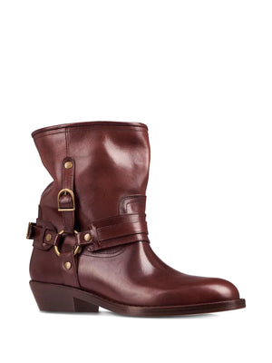 Close-up image of Ildred Boots in Brown, showcasing the antique gold-finish metal details and 100% bovine leather composition.