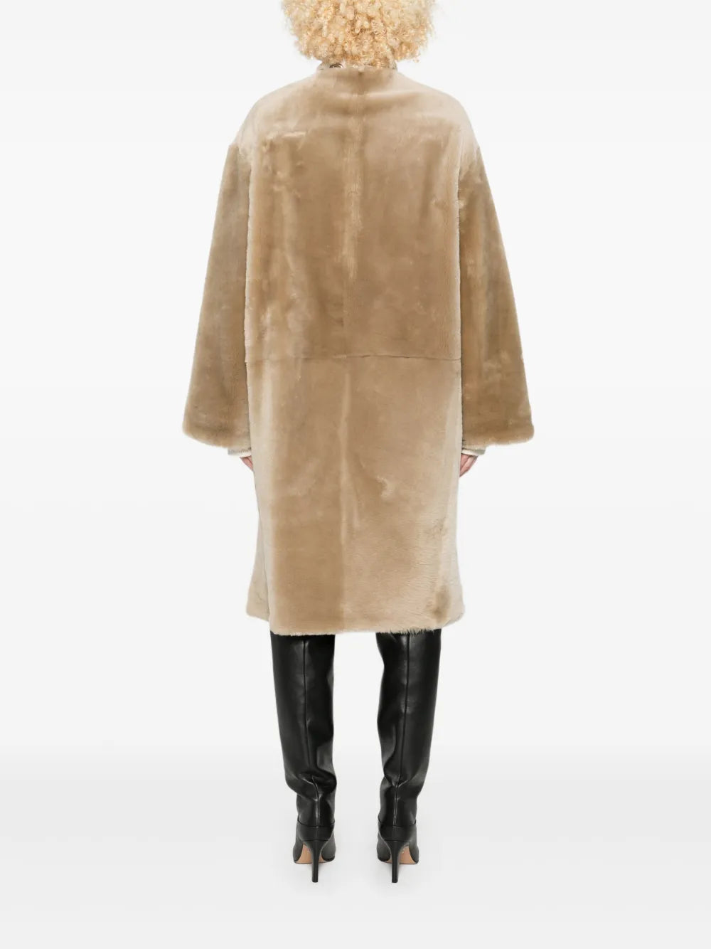 Close-up view of the collarless shearling coat in rye, emphasizing its luxurious lamb leather composition and unique collarless design.