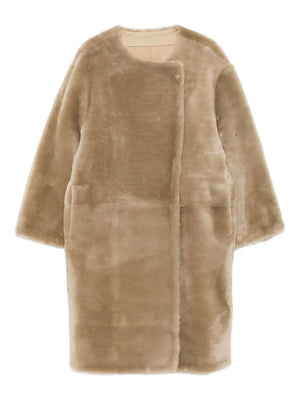 Stylish collarless shearling coat in rye, showcasing its soft suede-back texture and minimalist design from TOTEME's Fall Winter 25 collection.