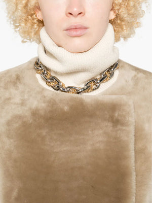 Full view of the collarless shearling coat in rye, offering a glimpse of its elegant silhouette and chic styling from TOTEME's latest collection.