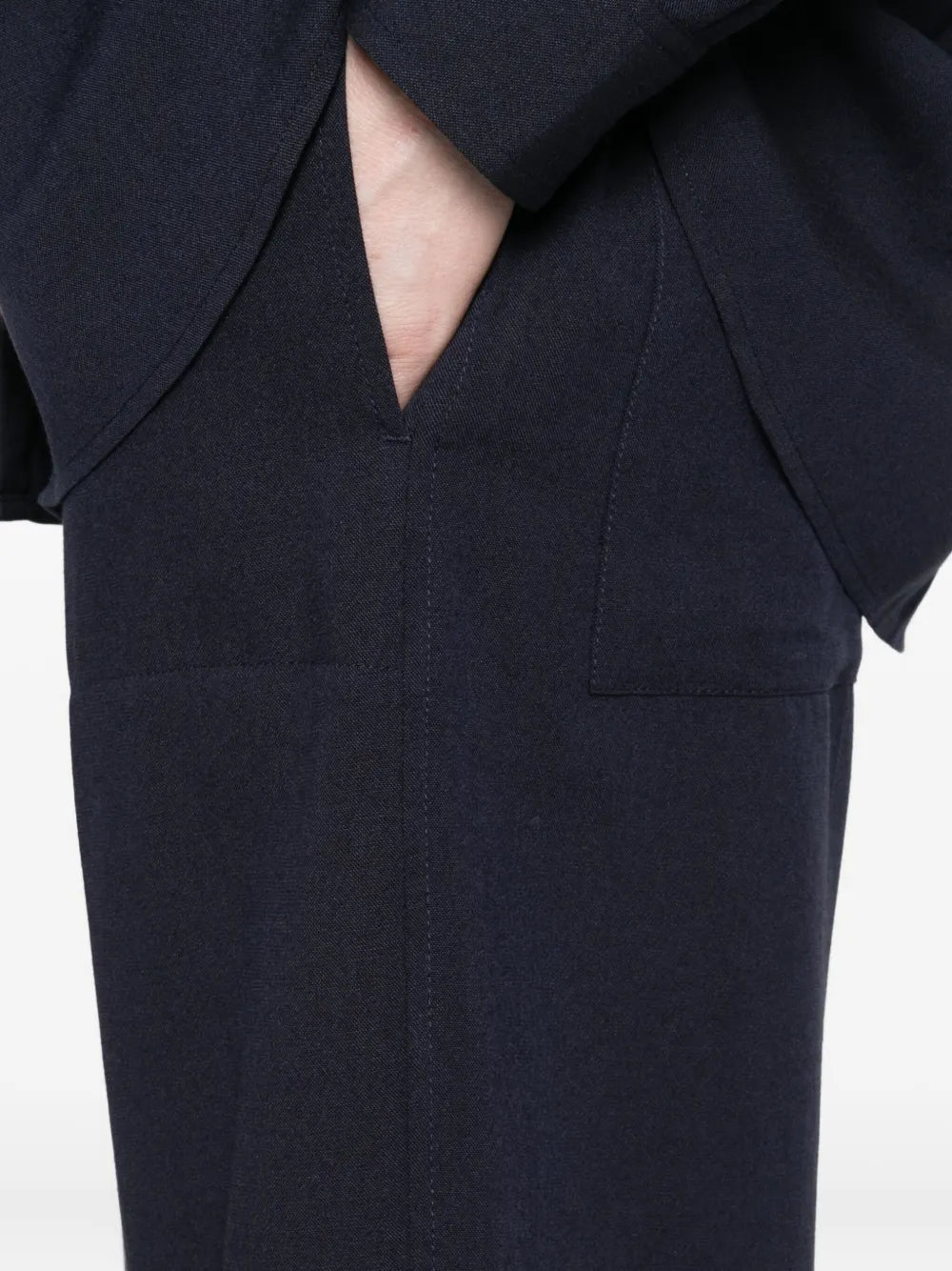 Fluid Winter Trousers in Navy from TOTEME displayed on a hanger, showcasing the sculptural flared legs and elegant design.