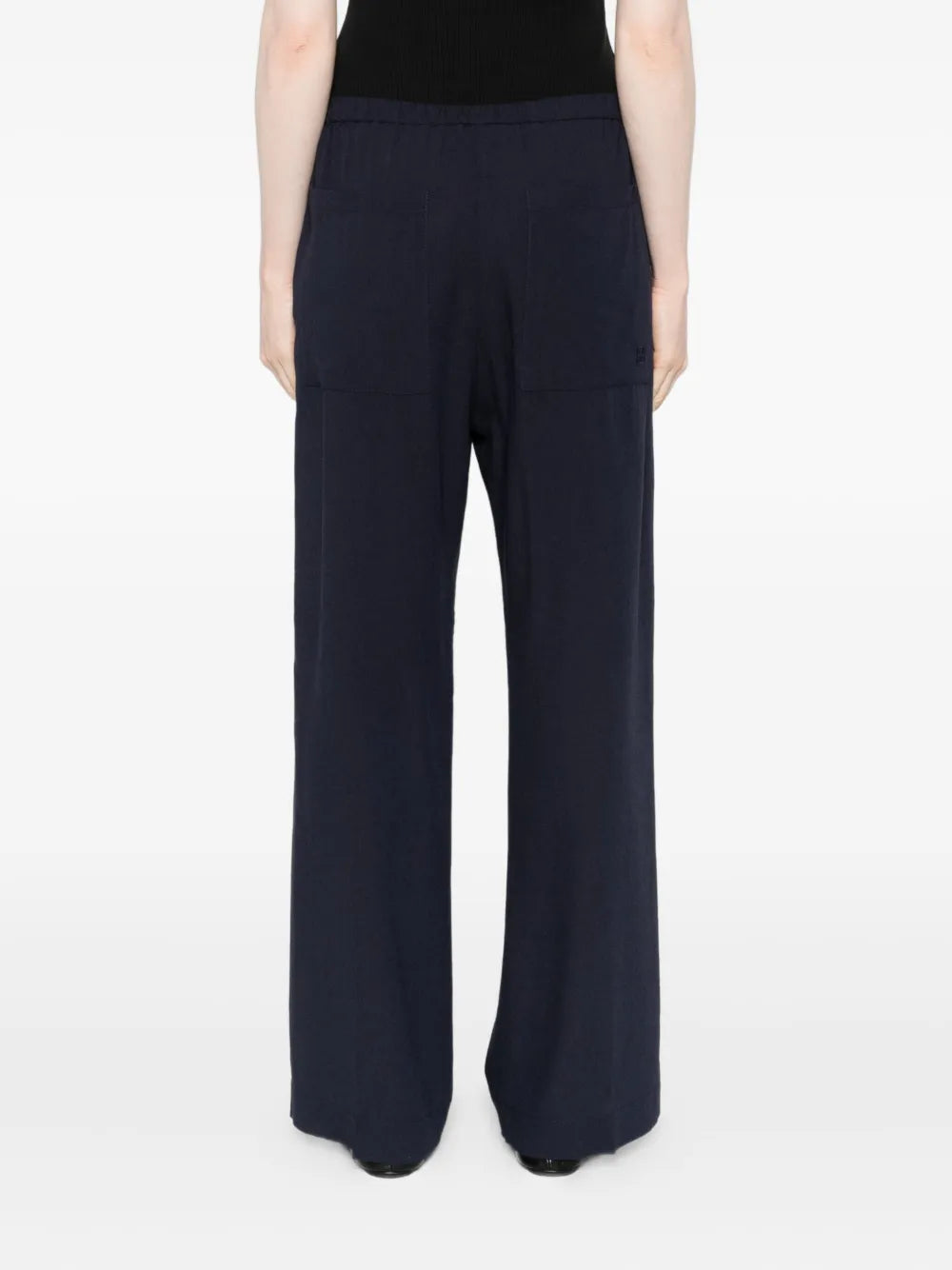 Model wearing Fluid Winter Trousers in Navy by TOTEME, paired effortlessly with a simple knit for a chic daytime outfit.