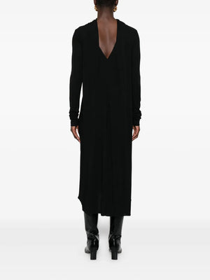 Side view of the black Cocoon Cape Dress by TOTEME, emphasizing its slightly dipped hem and cape-like design.