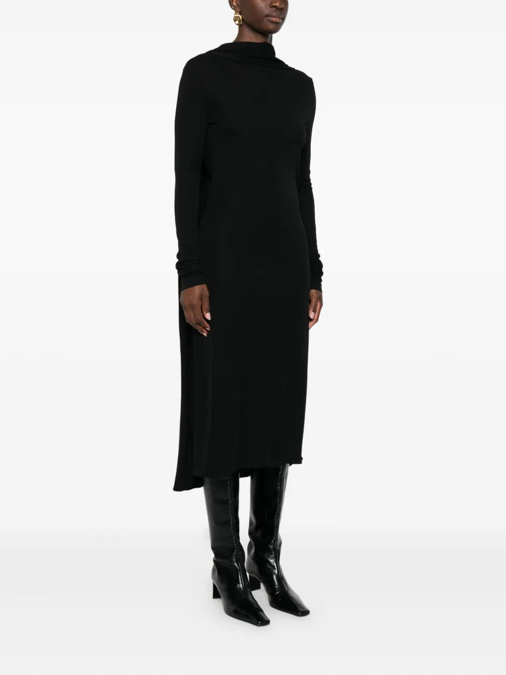 Model wearing the Cocoon Cape Dress in Black by TOTEME, styled with tonal accessories for a chic night out.