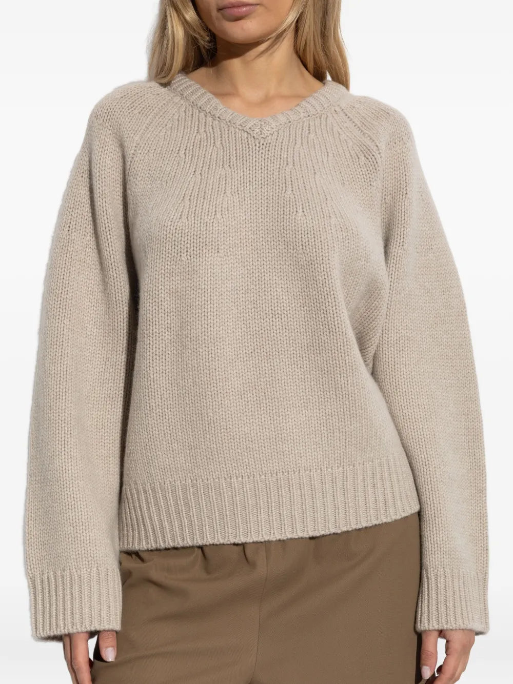 Model wearing Oia Sweater in Sand with a slightly curved back hem, styled for a casual look.