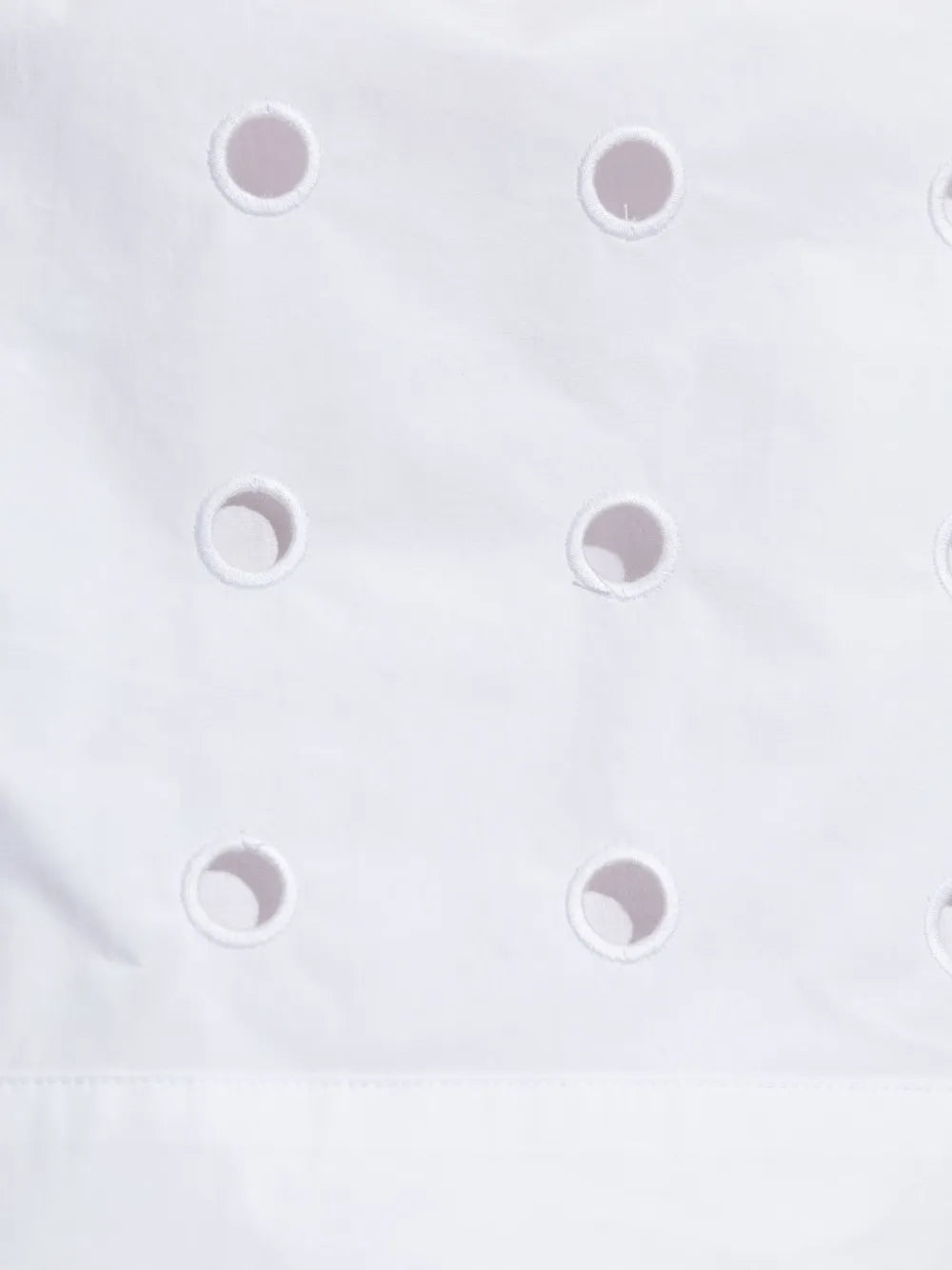 The Peggy Top in Vintage White laid flat, highlighting the high neckline and laser cut embroidery pattern.
