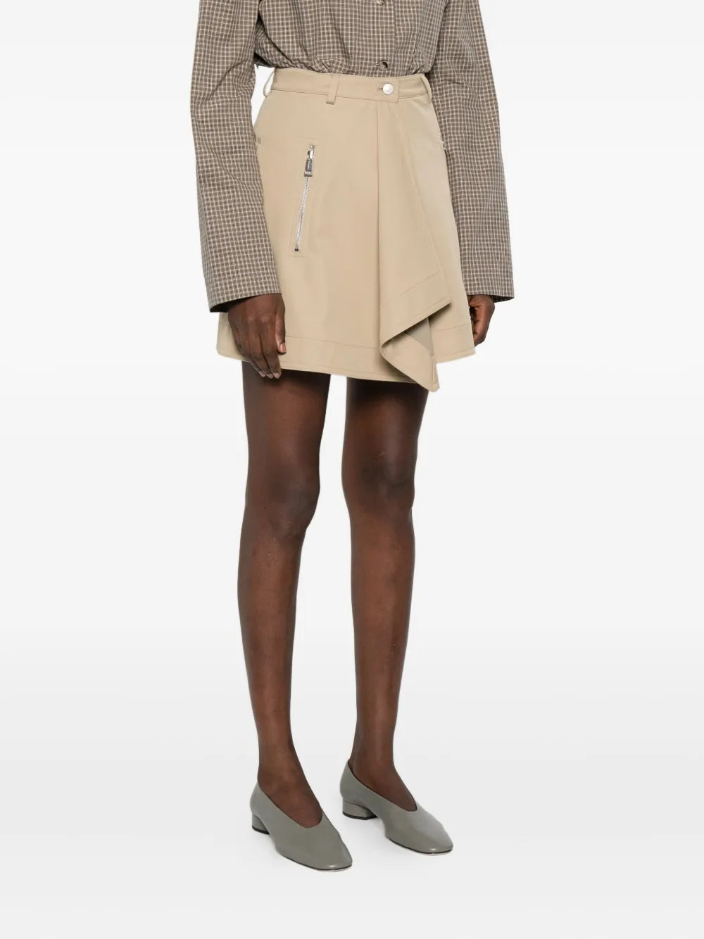 A model wearing the Inge Mini Skirt in Beige by Nanushka, perfect for a fashionable casual look.