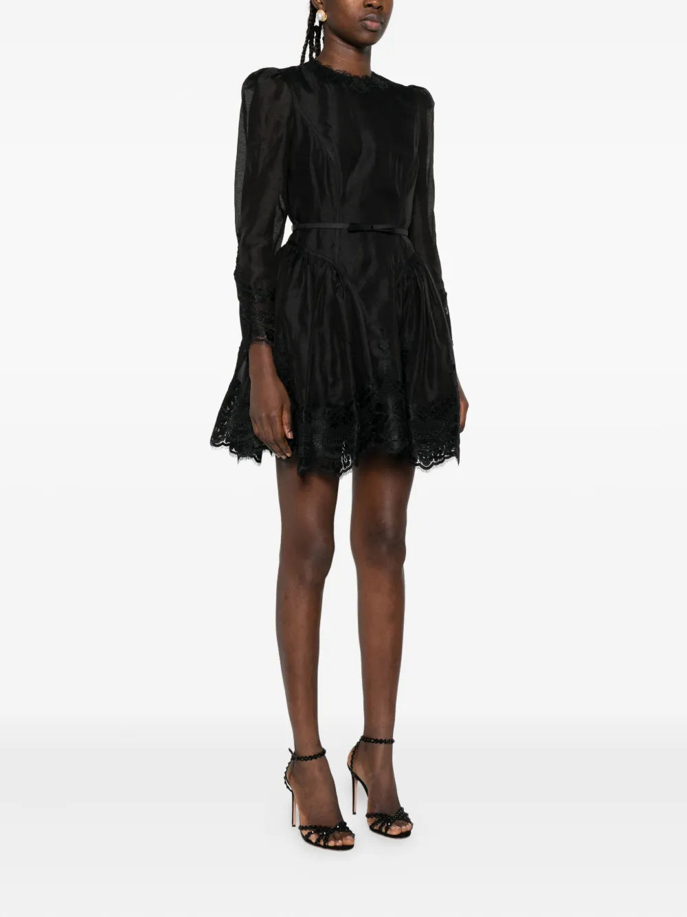 Model wearing Hypnotic Lace Trim Mini Dress in Black, displaying the flared skirt and long sleeves.