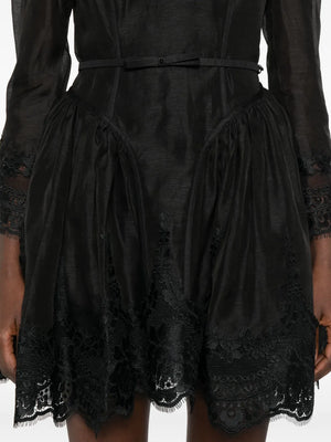 Full length image of the Hypnotic Lace Trim Mini Dress in Black against a stylish backdrop, showcasing its chic style.