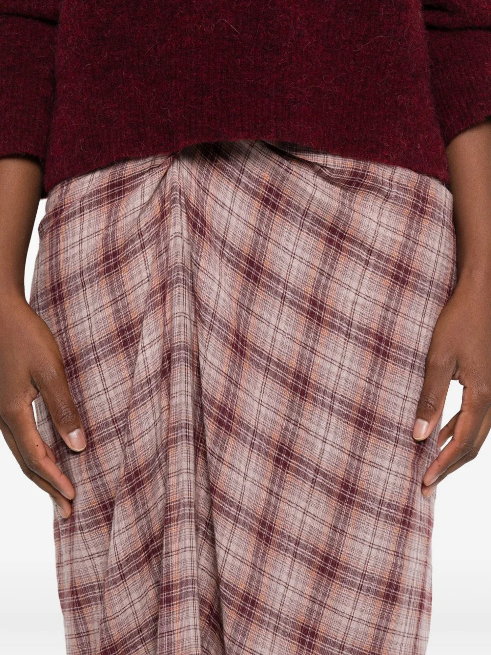 Side angle of the Nicole Skirt in Rosewood, illustrating its flowing fabric and checkered pattern in a chic setting.
