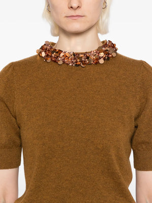 Lifestyle image of a model wearing the Liv Embroidered Cashmere Short Sleeve Knit in Umber by Ulla Johnson, perfect for any elegant occasion.