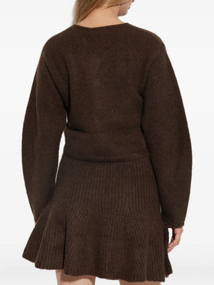 Model wearing the Zharea Cardigan in Dark Mahogany against a cozy backdrop, representing classic winter fashion.