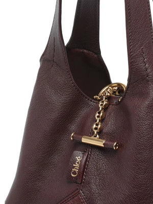Detailed view of the Small Chloé Balloon Bag in Grenat, featuring the signature Horse Medal at the base.