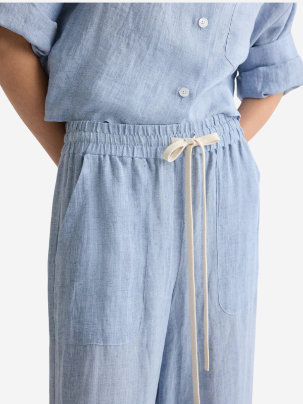 Flat lay of TWP Main Street Pant in Light Indigo, showcasing its unique color and material composition.