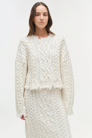 Lifestyle image featuring the Felix Knit Cropped Sweater in Ivory, paired with accessories for a trendy outfit.