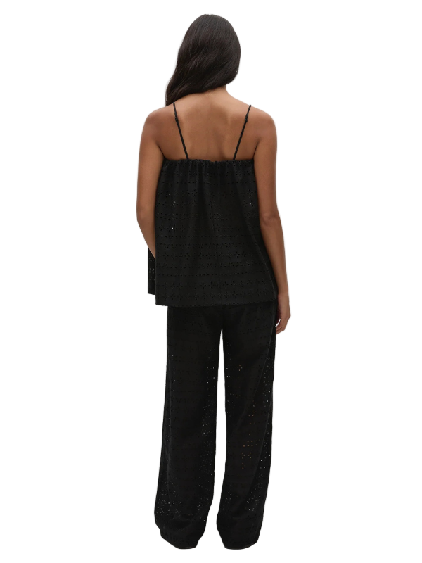Model wearing the Navia Top Agnes Broderie Anglaise in Black by FaithFull, featuring the flowing overlay and fitted under bodice for a chic look.