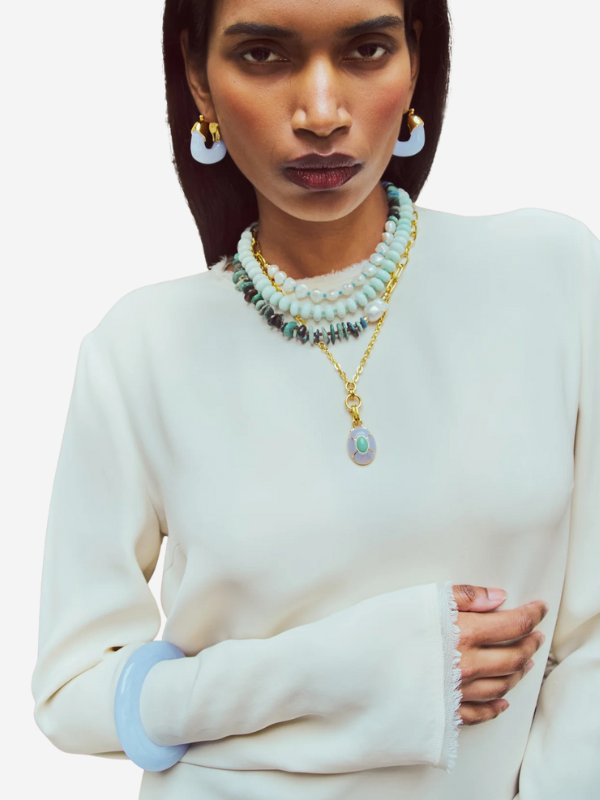 Styled shot of the Yucca Pendant Necklace in Gold worn layered with shorter beaded strands for a fashionable look.
