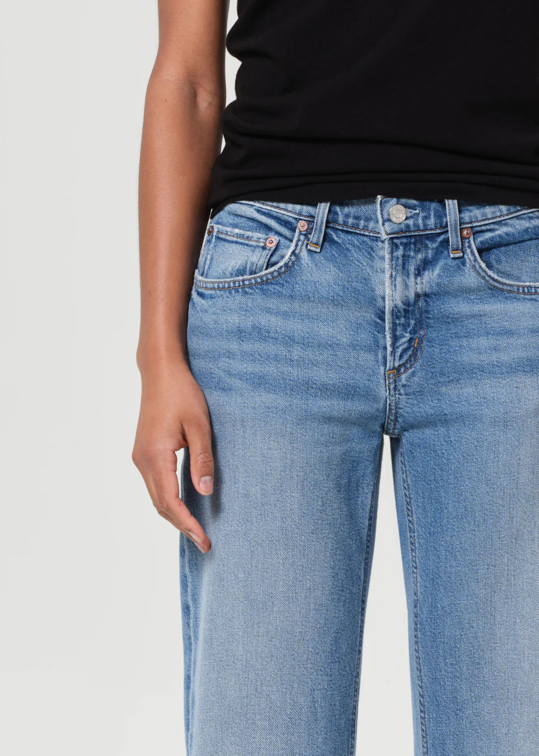 Agolde Low Rise Slim Stretch jeans in Kindle being styled with a crisp button-down shirt for a trendy everyday look.