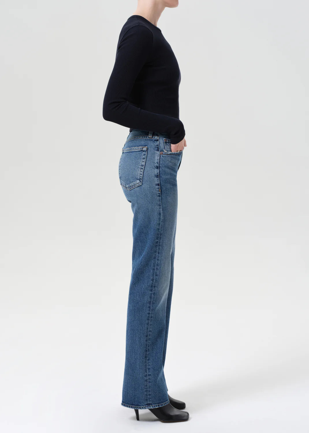 A model wearing Agolde Kick Boot Jean in Curve, paired with a slim knit top for a trendy look.