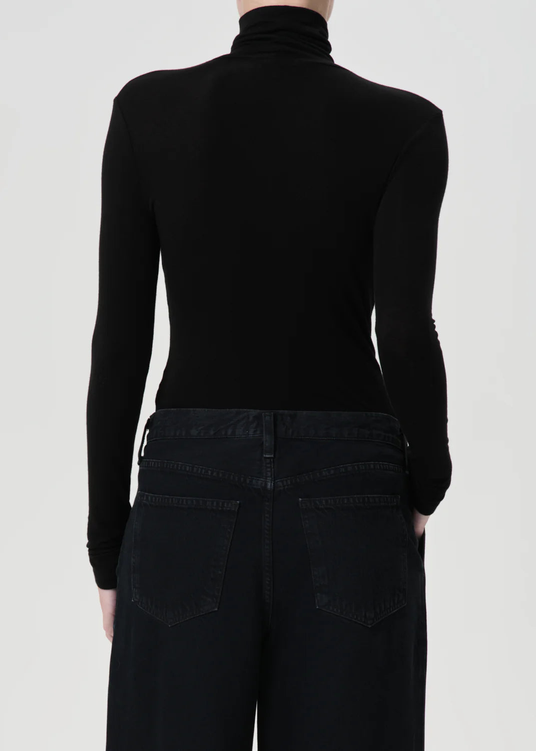 Model wearing the Agolde Pascale Turtleneck in Black paired with denim for a chic look.