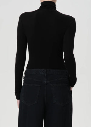 Model wearing the Agolde Pascale Turtleneck in Black paired with denim for a chic look.
