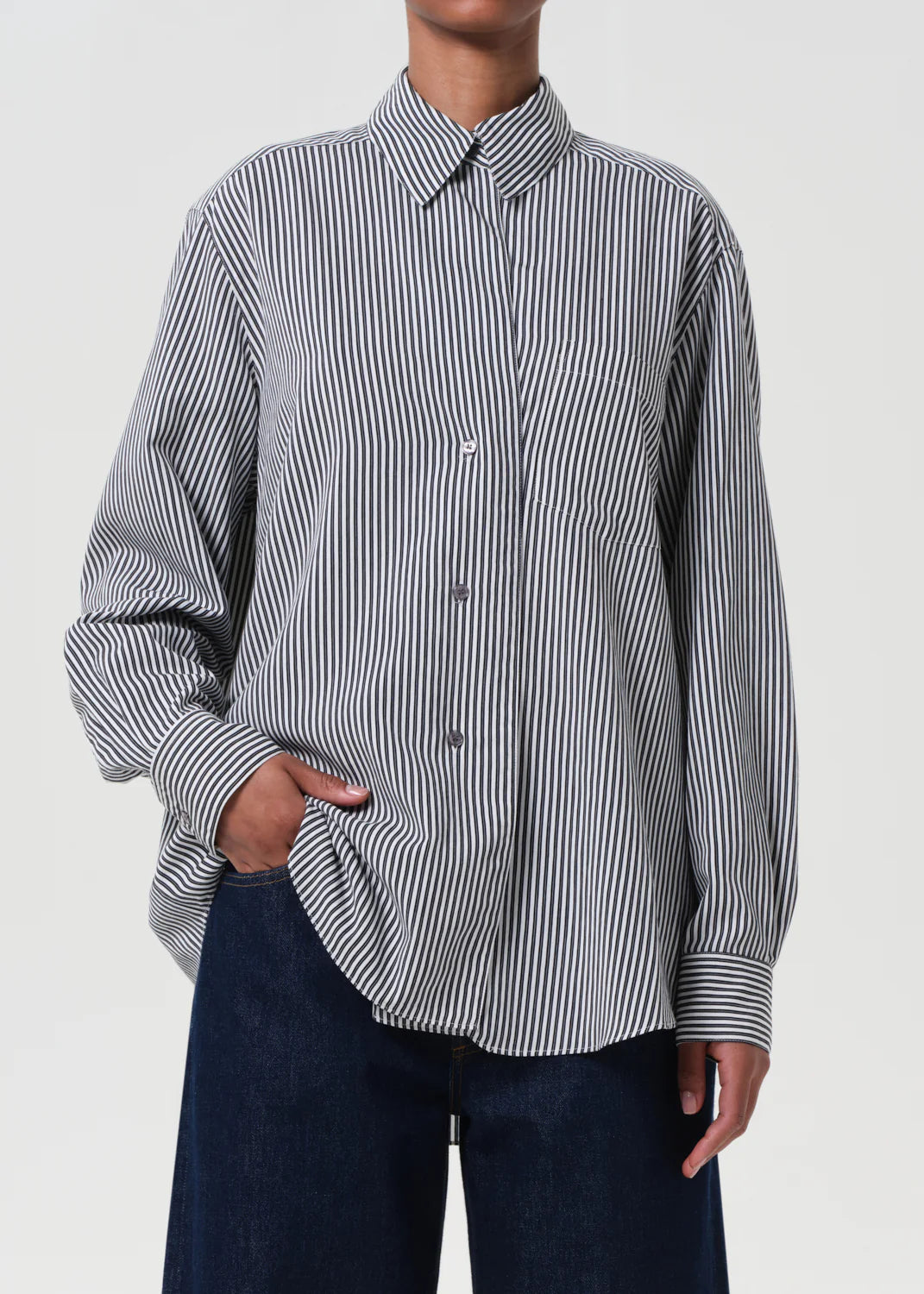 Model styling the Agolde Aris Shirt in Solene Stripe, half-tucked into tailored trousers.