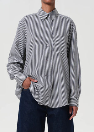 Model styling the Agolde Aris Shirt in Solene Stripe, half-tucked into tailored trousers.