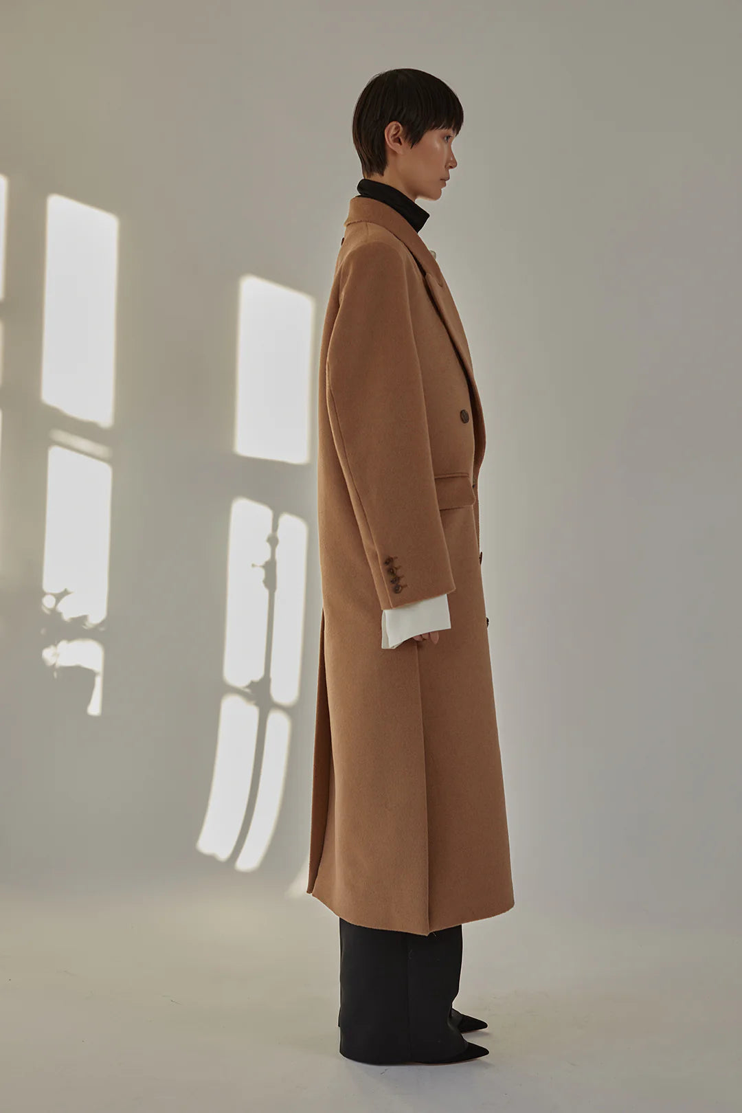 Side view of the Lilli Coat in Camel featuring its tailored midi length and side vents.