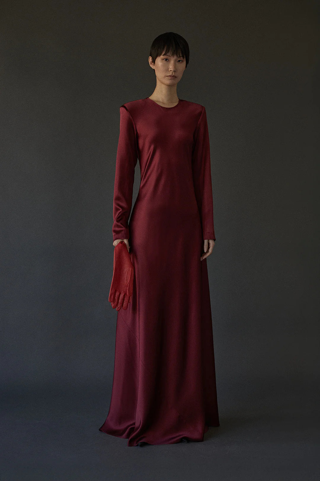 Ruth Dress in Burgundy displayed on a model, highlighting the graceful silhouette and invisible zipper back closure.