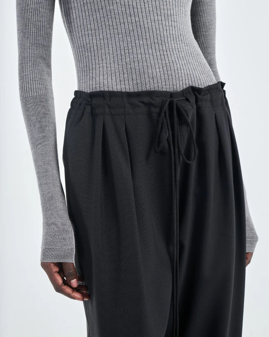 Barrel Leg Drawstring Pant in Black flat lay, showing the pleat front design and drawstring waist.