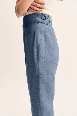 Close-up of Thea Trousers in Steel Blue on a hanger, showing the quality linen texture and sophisticated color.