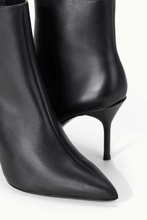 Staud Sebastian Ankle Boot in Black on a stylish backdrop, emphasizing its trendy look.