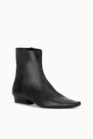 Side profile of the Wally Flat Ankle Boot in Black highlighting the elegant silhouette and 1-inch heel.