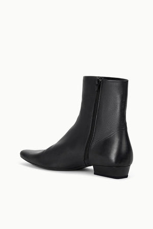 Wally Flat Ankle Boot in Black by Staud displayed in a stylish setting, emphasizing its versatility for outfits.