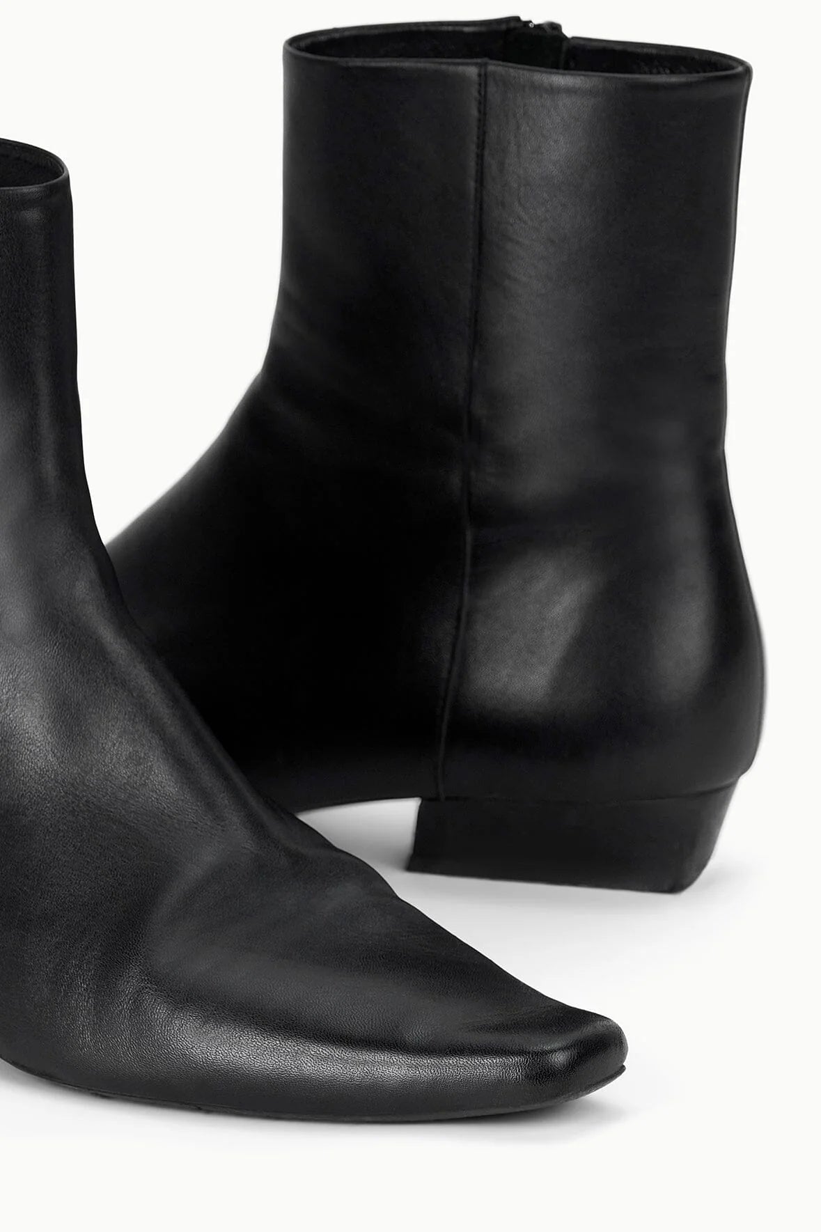 Wally Flat Ankle Boot in Black displayed on a rustic surface, emphasizing its trendy design and contrasting materials.