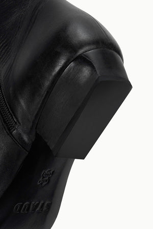 Wally Flat Ankle Boot in Black by Staud, highlighting the ankle height and sophisticated appearance.