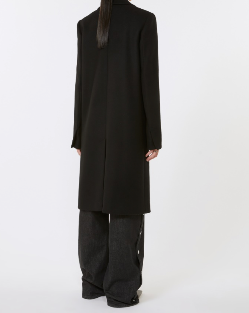 Close-up of the Ala Coat in Black highlighting its luxurious virgin wool composition and chic, cosmopolitan style.