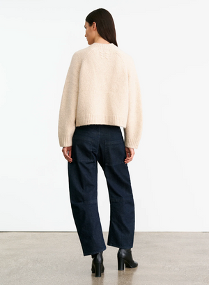Model wearing Tomaso Sweater in Beige Melange, highlighting its stylish raglan sleeves and ribbed hem.
