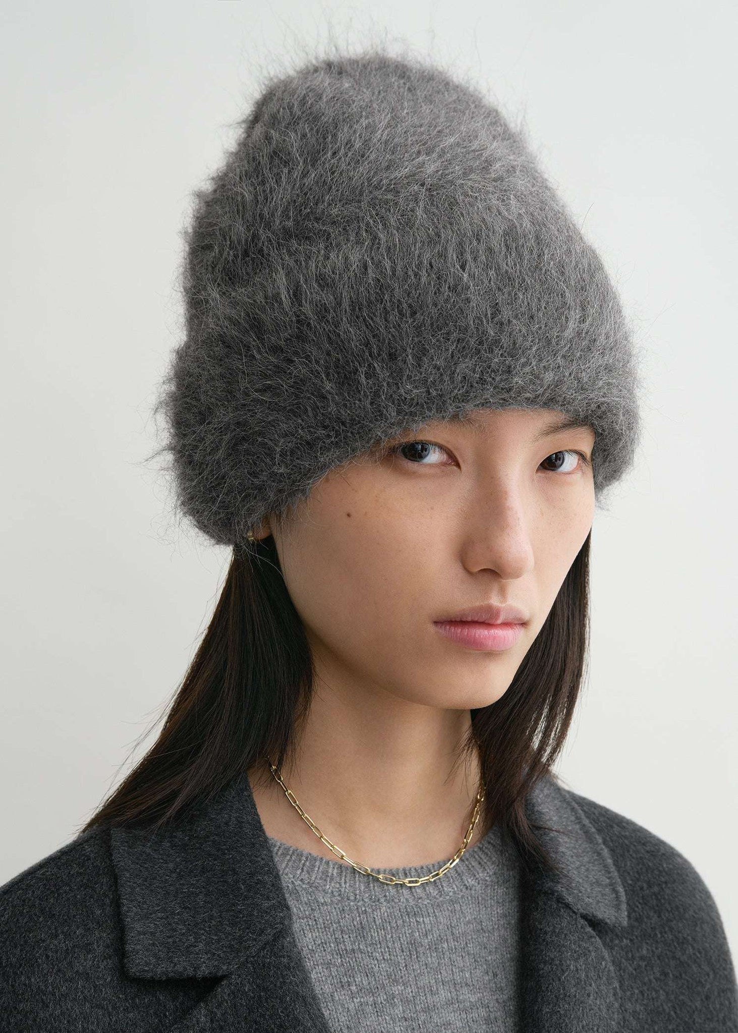 Alpaca Beanie Hat in Dark Grey Melange worn by a model, demonstrating its fashionable fold-over style and versatility from TOTEME.