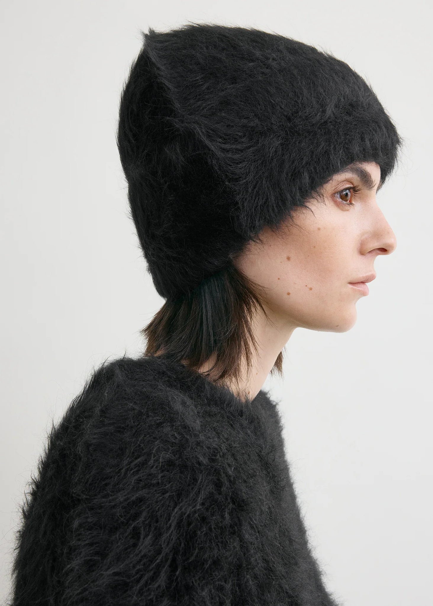 Alpaca Beanie Hat in Black from TOTEME displayed on a model, emphasizing its fashionable look.